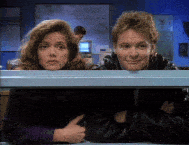 a man and a woman are looking out from under a table