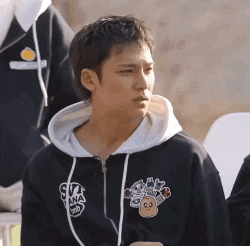 a man wearing a black sweatshirt with a sticker on it that says sya ana on it