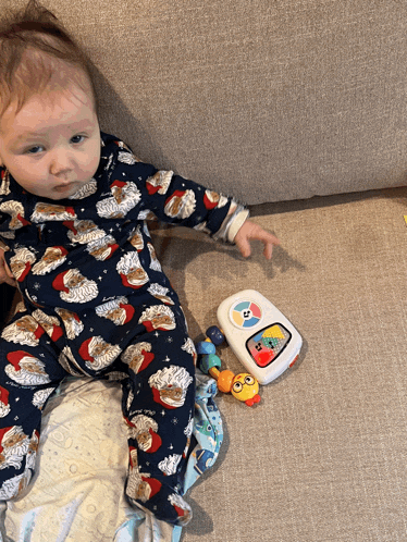 a baby is laying on a couch next to a toy that says ' fisher price ' on it
