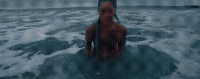 a man in a red hoodie is standing in the water
