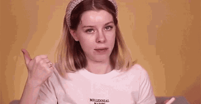 a woman is wearing a headband and a white t-shirt and making a funny face .