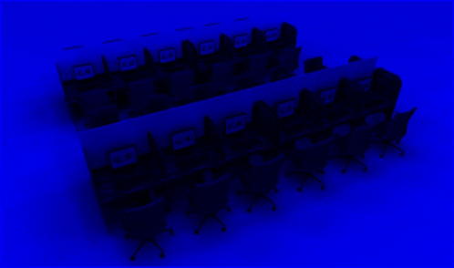 a row of cubicles with a blue background and a few computers on them