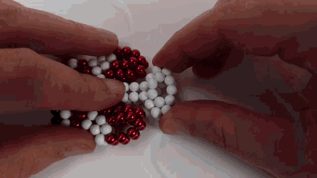 a person is playing with red and white beads on a table