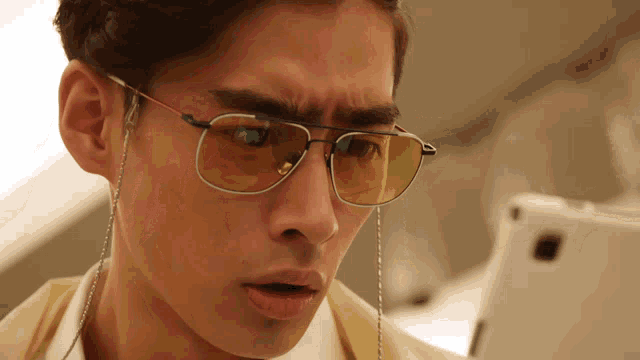 a close up of a man wearing sunglasses looking at a tablet