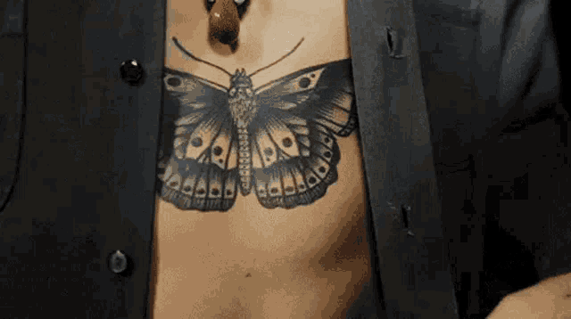 a close up of a person 's chest with a butterfly tattoo .