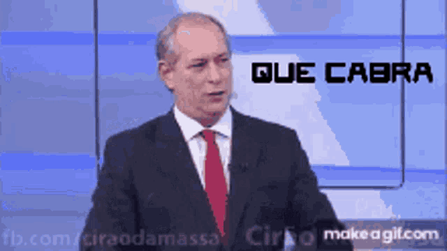 a man in a suit and tie stands in front of a screen that says que cabra on it