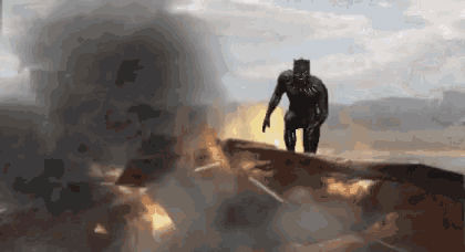 a man in a black suit is standing on a rock in front of a fire