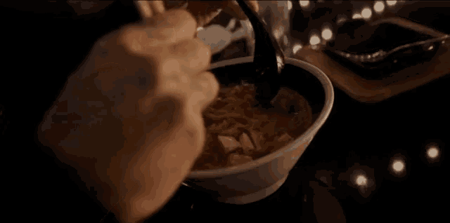 a person is eating a bowl of noodles with chopsticks .