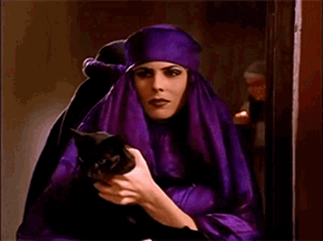 a woman in a purple robe is holding a cat
