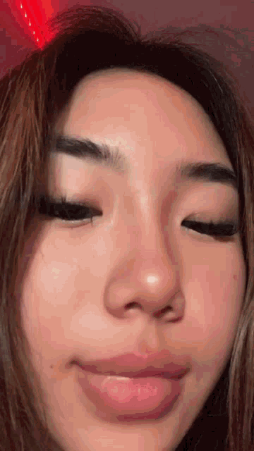 a close up of a young woman 's face with her eyes closed .