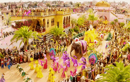 a large crowd of people are gathered in front of a building with a purple elephant in the middle