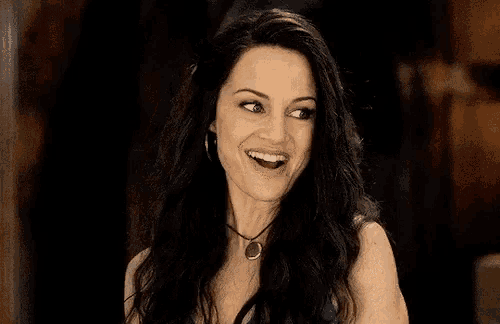 the woman is wearing a necklace and smiling .