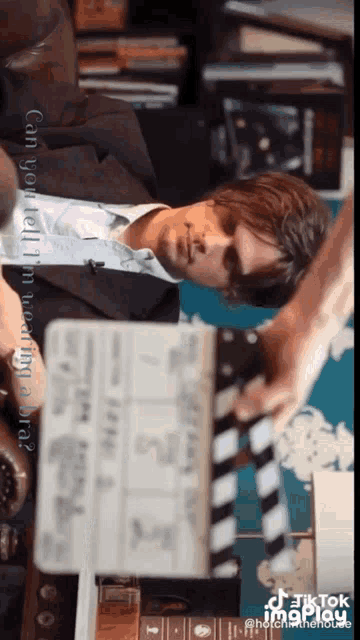 a man in a suit is laying on a clapper board with the caption " can you tell i 'm wearing bra "