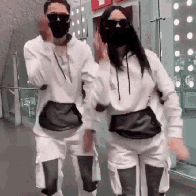 a man and a woman wearing face masks and sunglasses are dancing together .
