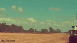 a white truck is driving through a dirt field with a blue sky behind it