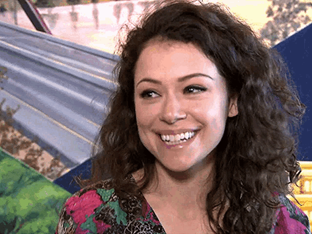 a woman with curly hair and a floral shirt is smiling