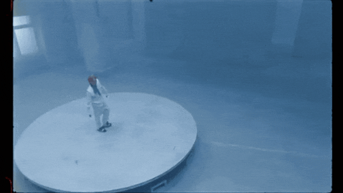 a man in a white suit is standing on a circular stage
