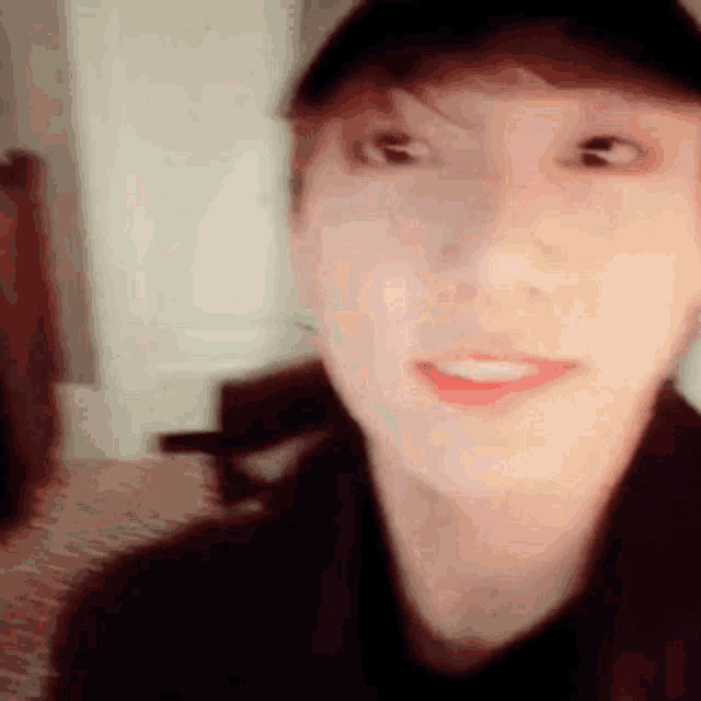 a close up of a person 's face wearing a baseball cap and smiling .
