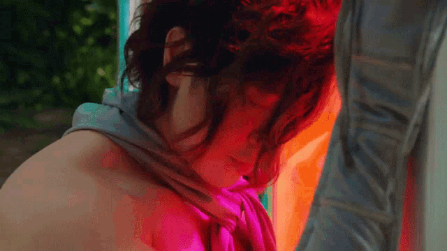a woman with a pink scarf around her neck looks down at something