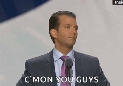 a man in a suit and tie is talking into a microphone and says c ' mon you guys