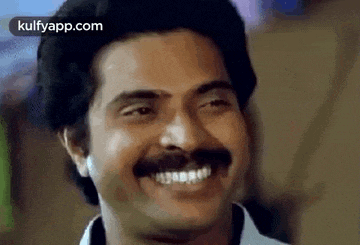 a man with a mustache is smiling with his mouth open .