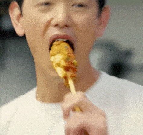 a man in a white shirt is eating a skewer of food .