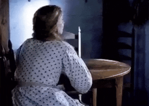 a woman is sitting at a table in a dark room .