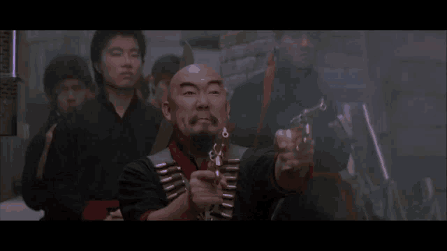 a man with a beard is pointing a gun at someone in a dark room