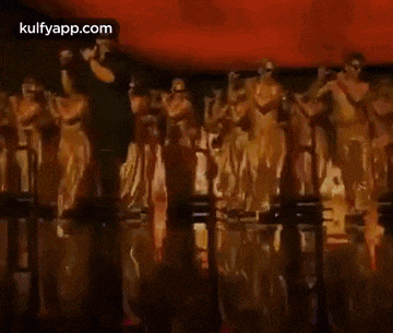 a man is dancing in front of a crowd of cheerleaders in a dark room .