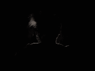 a silhouette of a man in a dark room with a light shining on his face