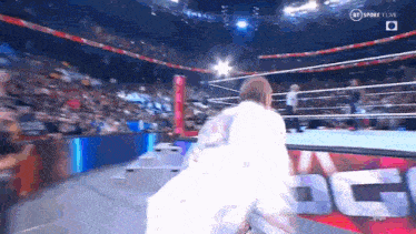a man is standing in a wrestling ring with a crowd watching .