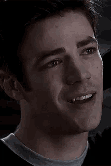 a close up of a man 's face with a smile on his face and a black background .