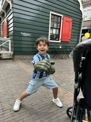 a young boy is holding a green hulk hand