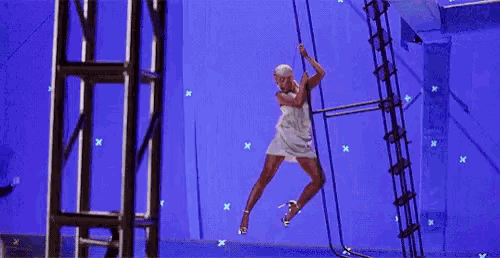 a woman is hanging from a rope while a man watches .