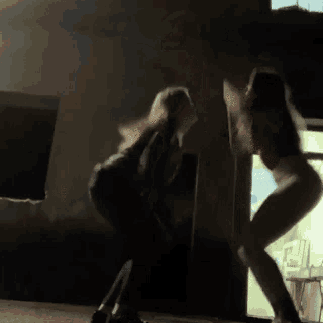 two women are dancing in a dark room and one of them is wearing a red tank top