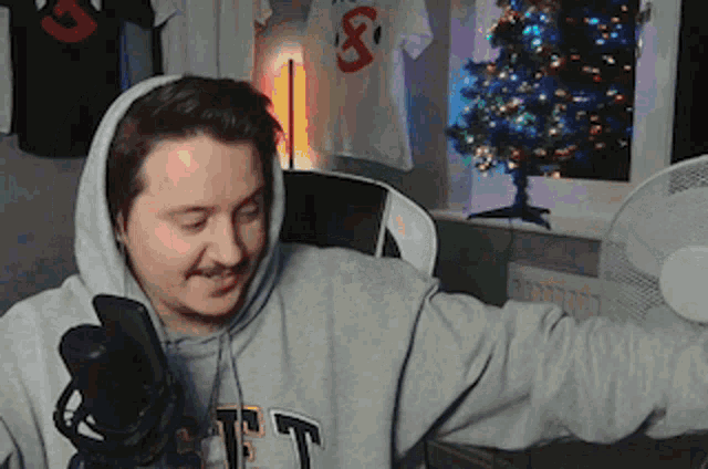 a man wearing a hoodie is standing in front of a microphone .