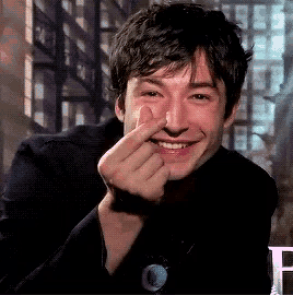 a young man is smiling and making a heart with his finger