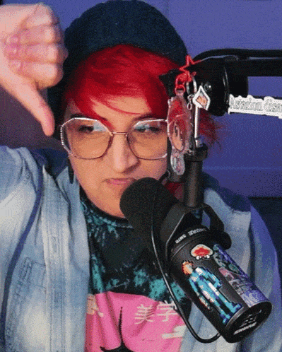 a woman with red hair is giving a thumbs down in front of a microphone