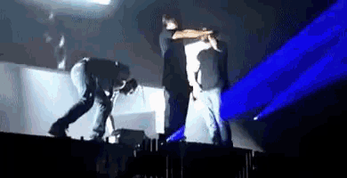 a group of men are standing on a stage with blue lights behind them .