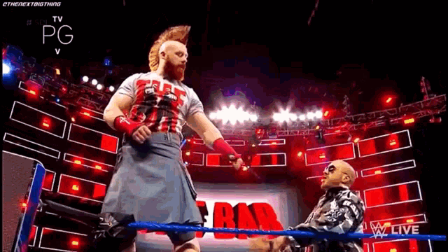 a wrestler in a kilt is standing in a wrestling ring with another wrestler .