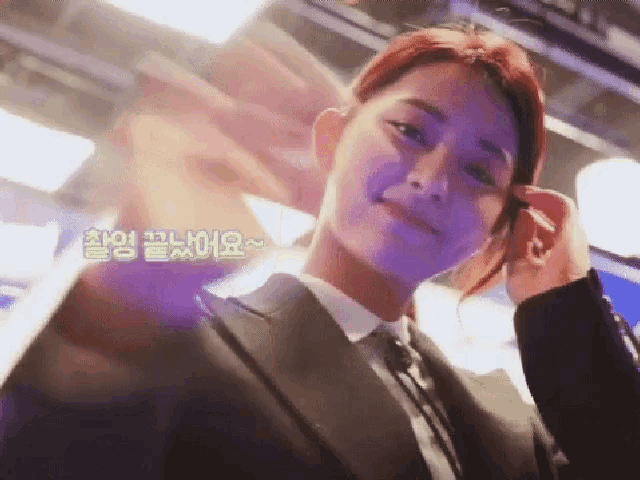 a woman in a suit and tie waves her hand in a foreign language