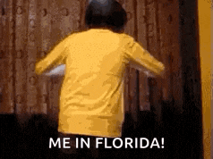 a person in a yellow shirt is dancing in front of a curtain .