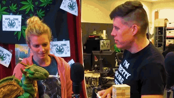 a man wearing a black shirt that says " i 'm berry rude " talks to a woman