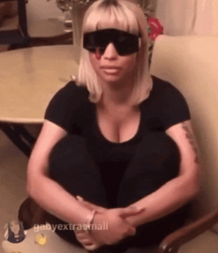 a woman wearing sunglasses and a black shirt sits on a chair