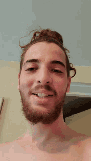 a shirtless man with a beard is smiling