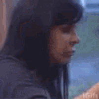 a woman with long black hair is holding a cell phone in her hand .