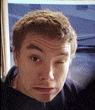 a young man is making a funny face in front of a computer screen .