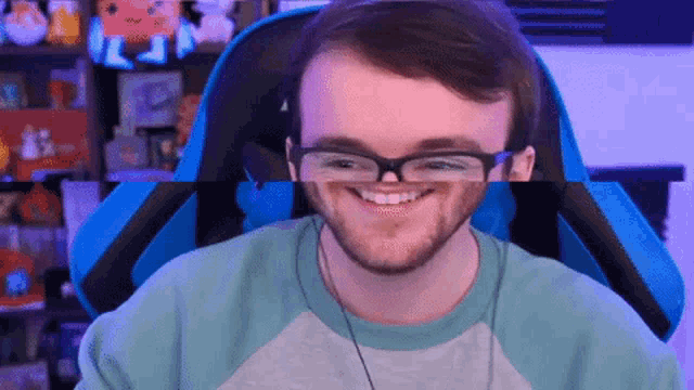 a man wearing glasses is smiling while sitting in a gaming chair