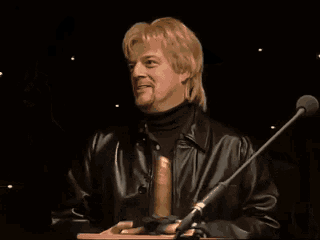 a man in a leather jacket is holding a golden penis in his hand