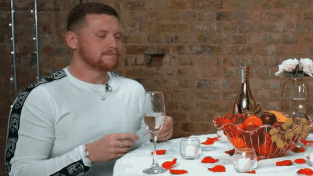 a man sits at a table with a glass of wine